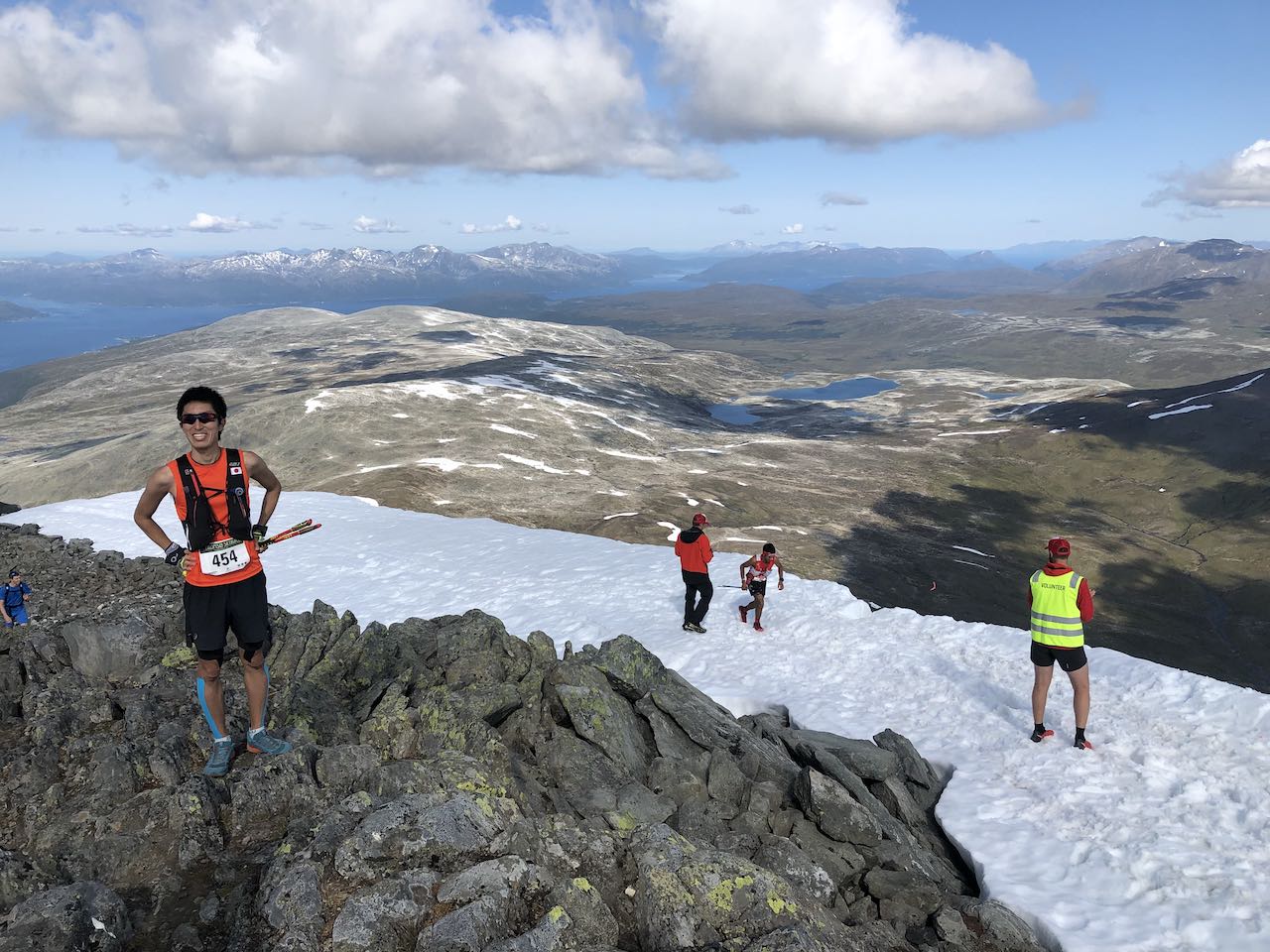 Picture from the top of the mountain with a person in the back who just scrambled up the snow patch