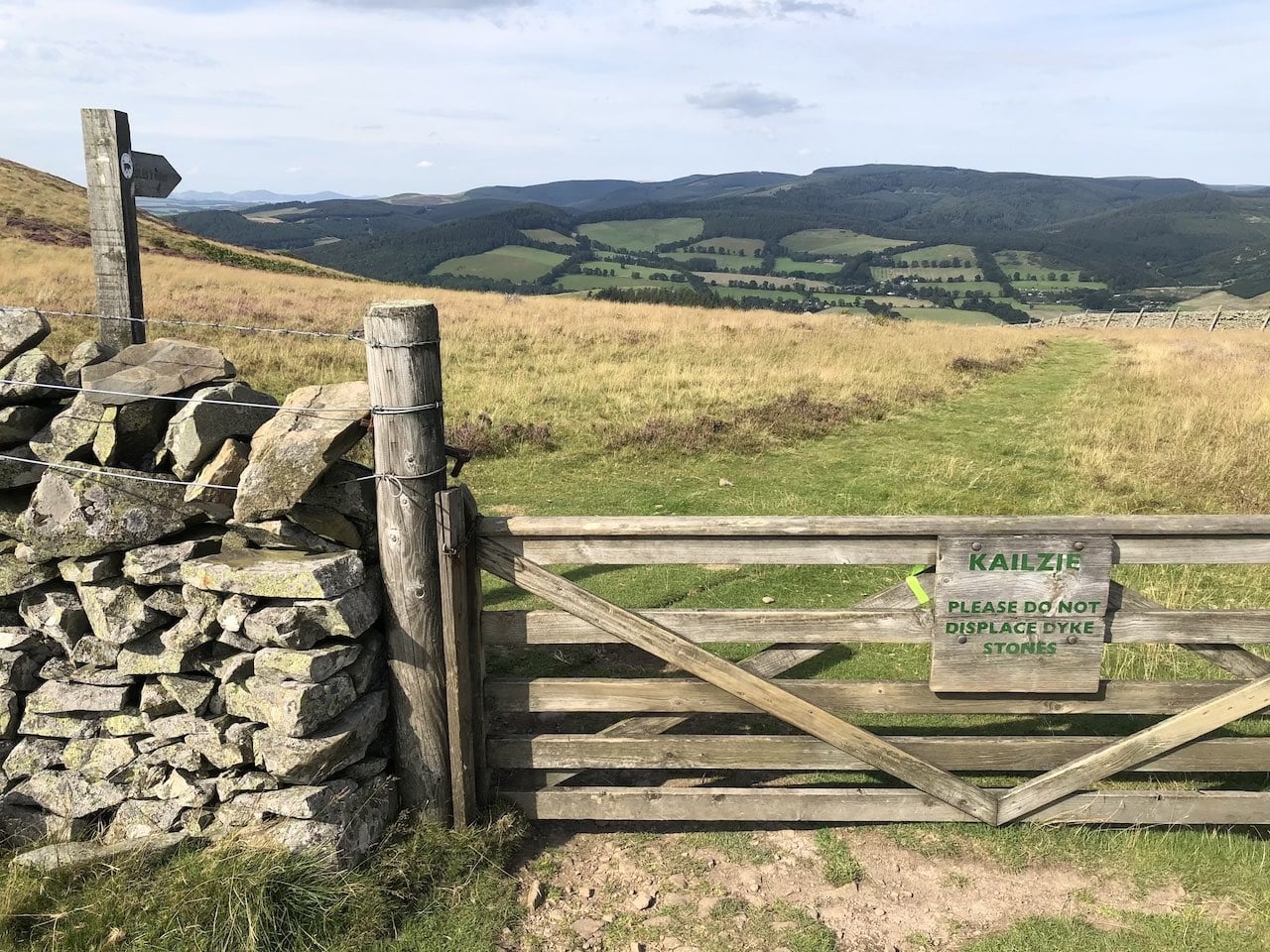 Beautiful view on a field with stone wall & a gate.